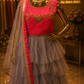 A pink and gray tiered tulle ethnic gown displayed on a gold mannequin in a boutique. The dress features a bright pink embroidered bodice, a layered gray tulle skirt, and a matching pink and gray dupatta with gold borders.