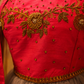 Close-up of a bright pink traditional blouse with intricate gold embroidery, beadwork, and a sheer gray tulle skirt.